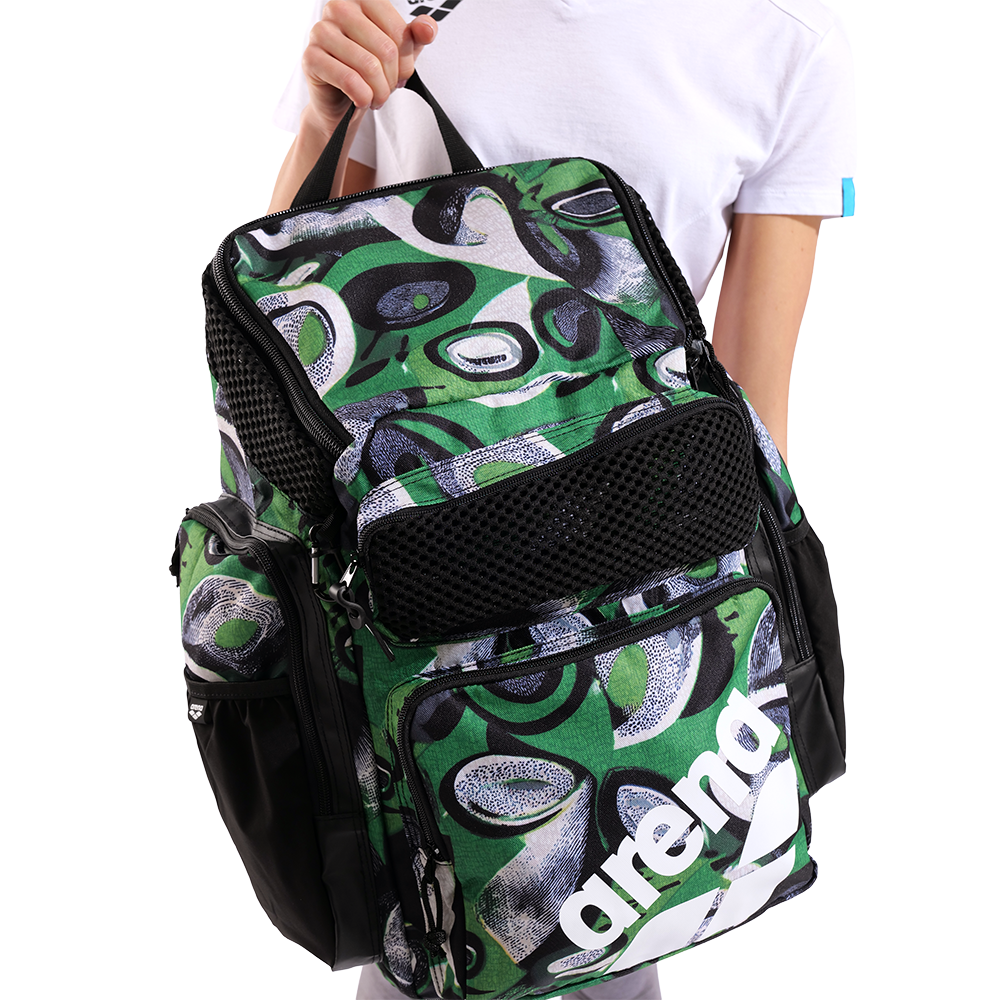 Green and black patterned backpack with 'arena' branding held by a person.