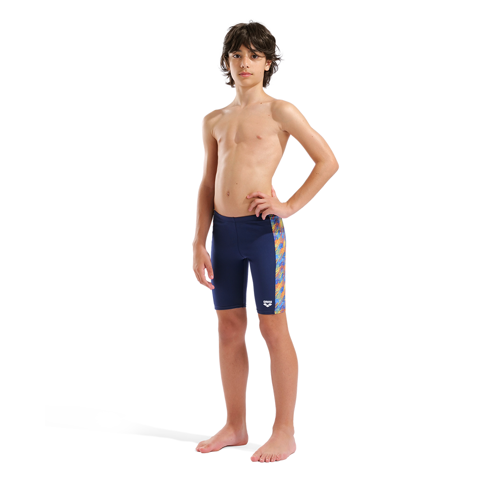 Young boy wearing Arena Boy's Draft Jammer blue swim shorts with a colorful pattern on a white background